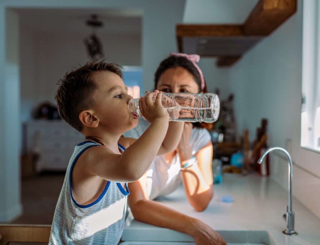 Mother and her toddler filling a glass with filtered water right from the tap